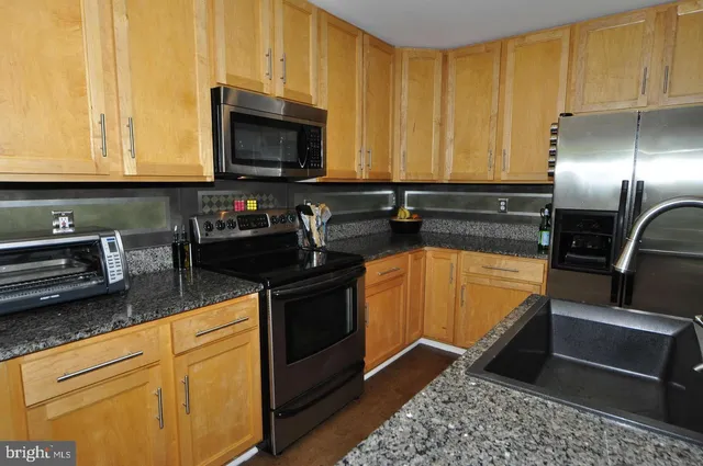 a kitchen with stainless steel appliances granite countertop a sink stove and microwave