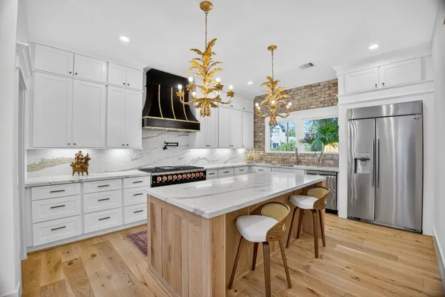 a kitchen with stainless steel appliances a stove a refrigerator and a kitchen island