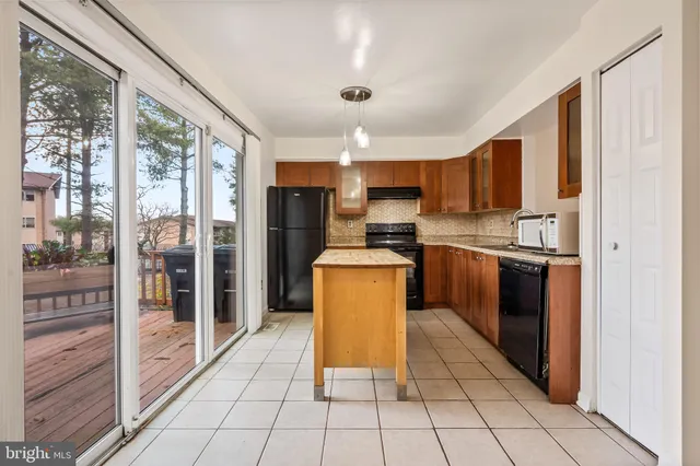 a kitchen with granite countertop a refrigerator a sink a stove top oven and cabinets
