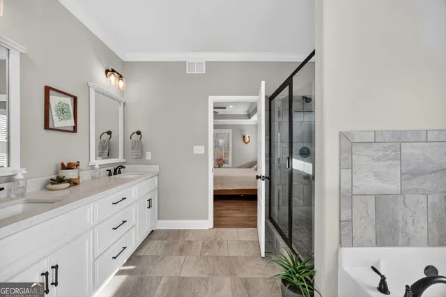 a en suite bathroom with a double vanity sink a large mirror and a shower