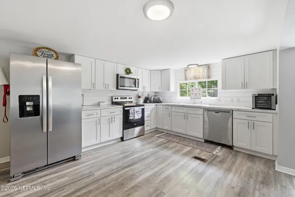a kitchen with white cabinets and stainless steel appliances