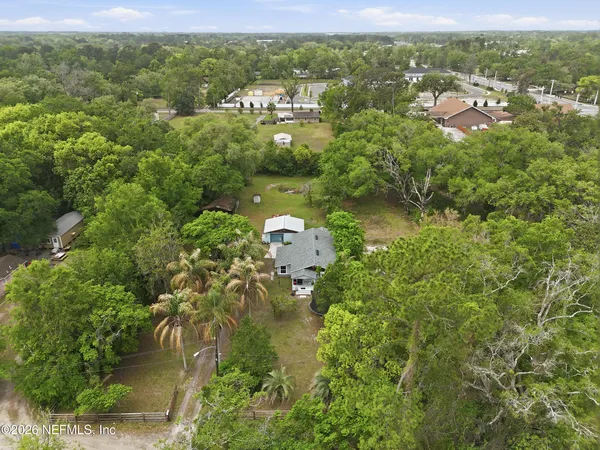 an aerial view of residential houses with outdoor space and trees