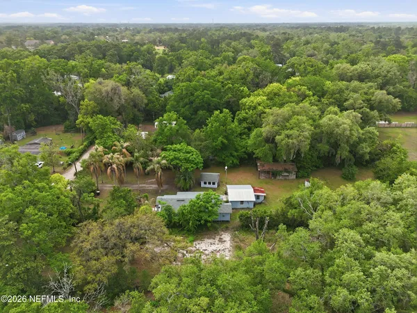 an aerial view of residential houses with outdoor space and trees