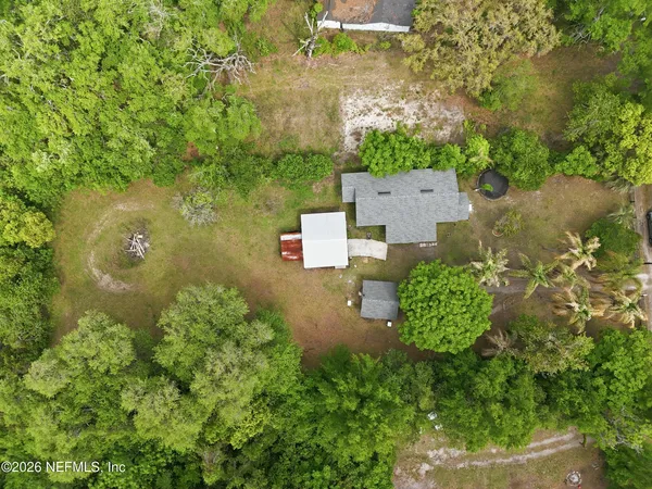 an aerial view of residential house with outdoor space and trees all around