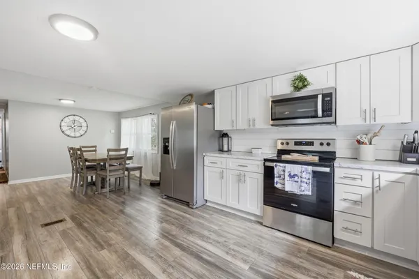 a kitchen with granite countertop a refrigerator stove microwave and cabinets