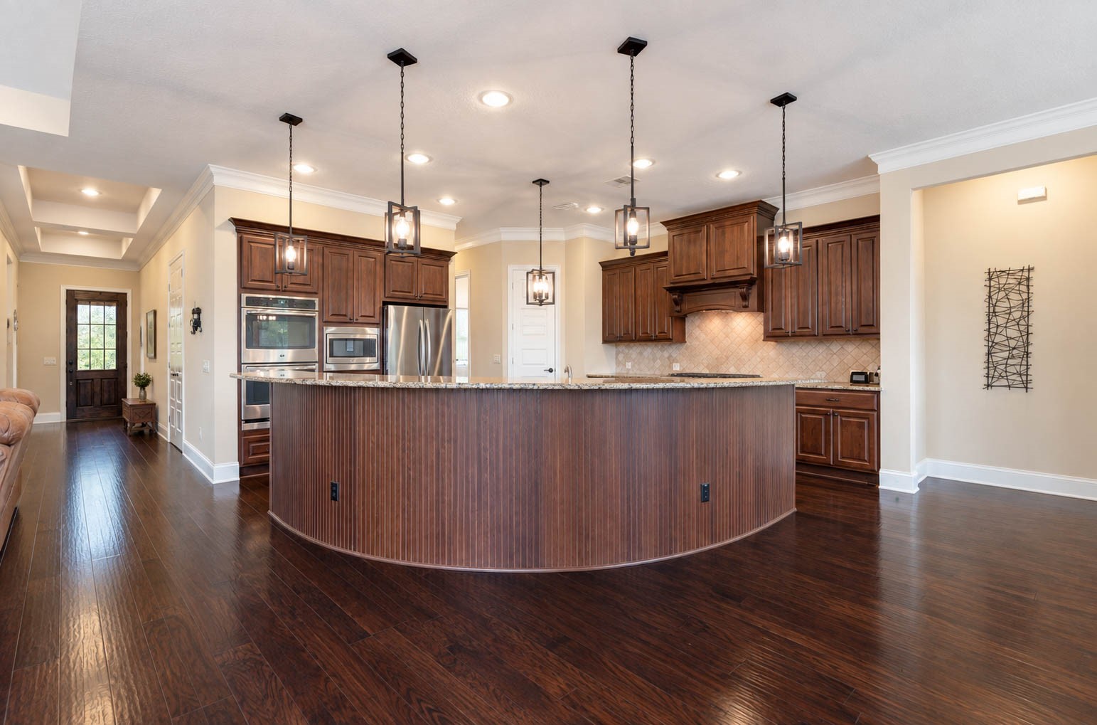 91 Lake View Loop Fulshear, TX 77441 - Photo 20 of 42 Check out this stunning arched breakfast bar island with wood accents, a true focal point of the kitchen. This view highlights the kitchen's convenient location near the front door. Every detail of this home was beautifully thought out.