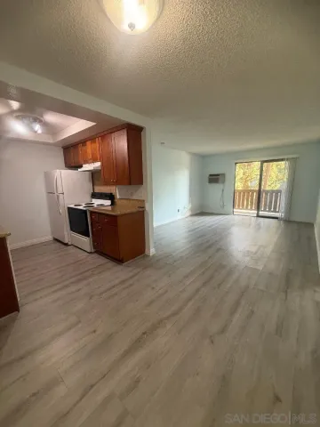 a large room with kitchen space and wooden floor