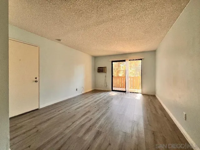 a view of an empty room with wooden floor and window