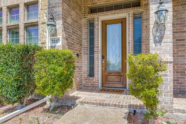 front view of a brick house with a large window and potted plants