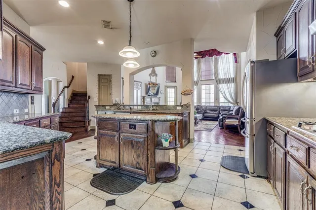a open kitchen with stainless steel appliances kitchen island granite countertop a stove a sink and a refrigerator