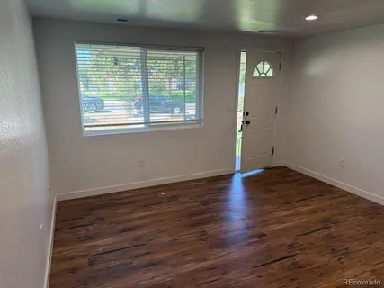 a view of an empty room with wooden floor and a window