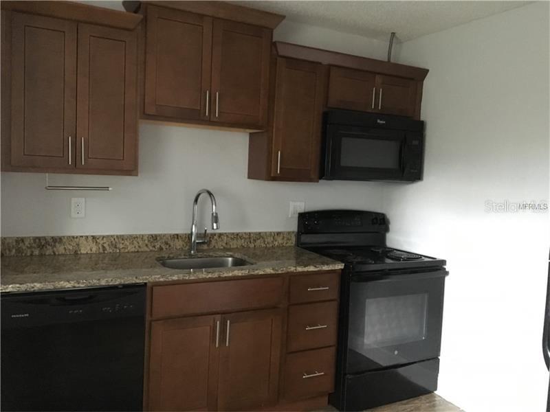 508 Varsity Street Winter Garden, FL 34787 - Photo 4 of 10 a kitchen with granite countertop white cabinets and black appliances