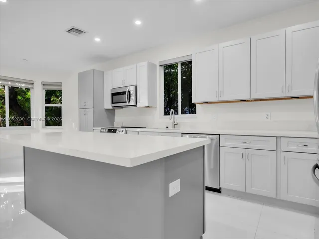a kitchen with kitchen island a sink stainless steel appliances and cabinets