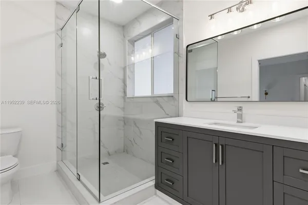 a bathroom with a granite countertop sink toilet and shower