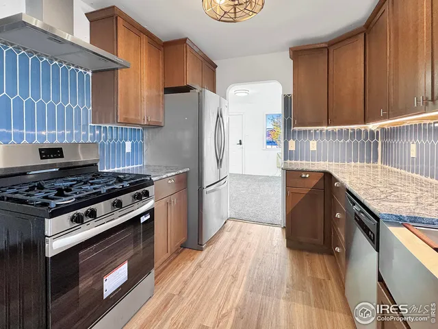 a kitchen with a stove a refrigerator and wooden floor