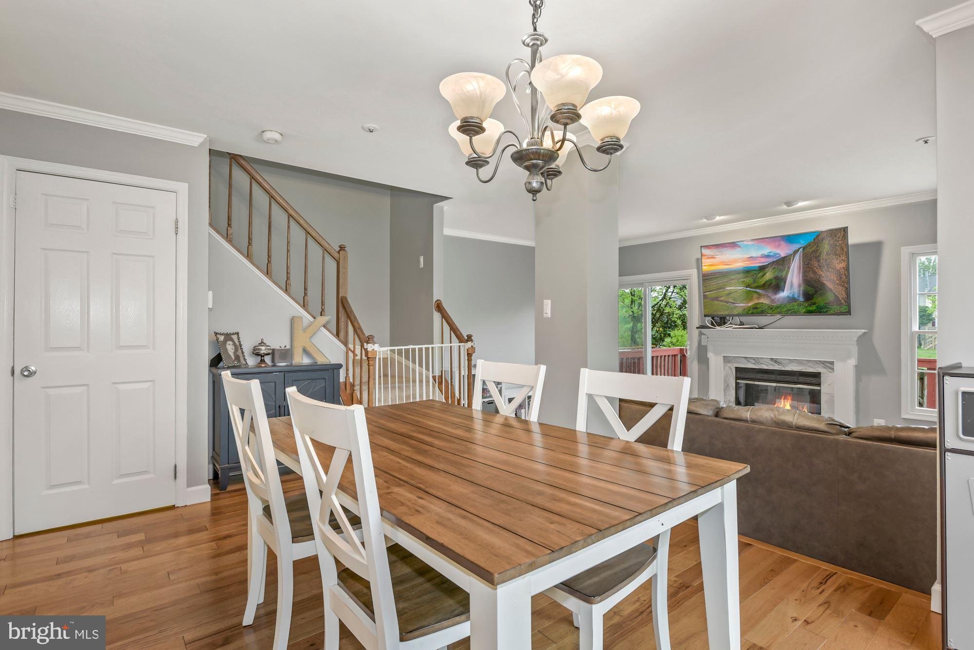 20121 Crew Square Ashburn, VA 20147 - Photo 13 of 36 a dining room with wooden floor a chandelier a wooden table and chairs