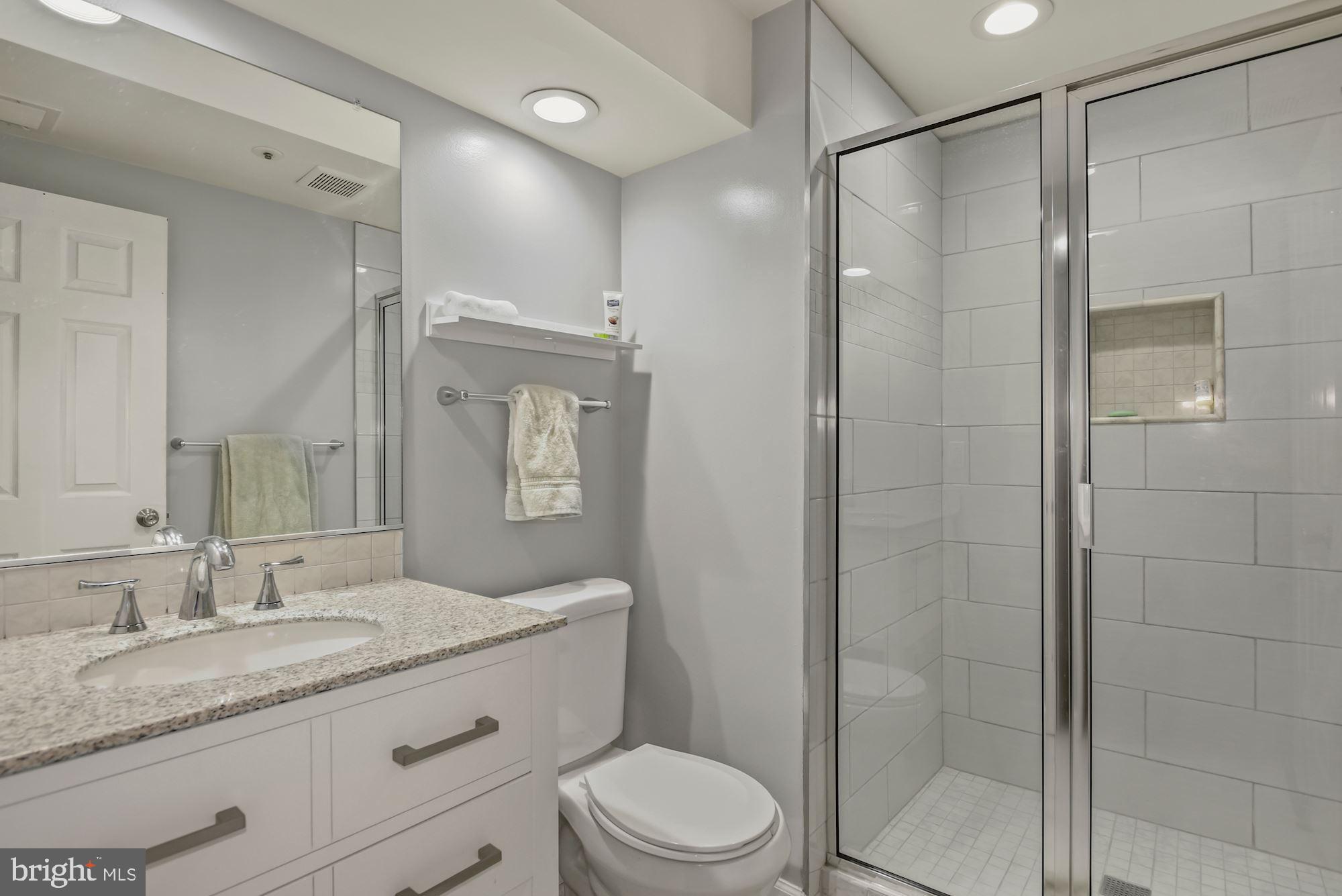 20121 Crew Square Ashburn, VA 20147 - Photo 30 of 36 a bathroom with a granite countertop sink toilet a mirror a vanity and shower