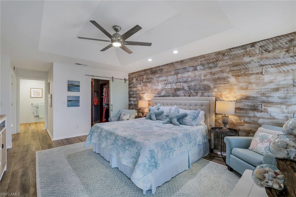 9101 Vanderbilt Drive, Unit 1302 Naples, FL 34108 - Photo 11 of 24 a bedroom with a bed couch and ceiling fan