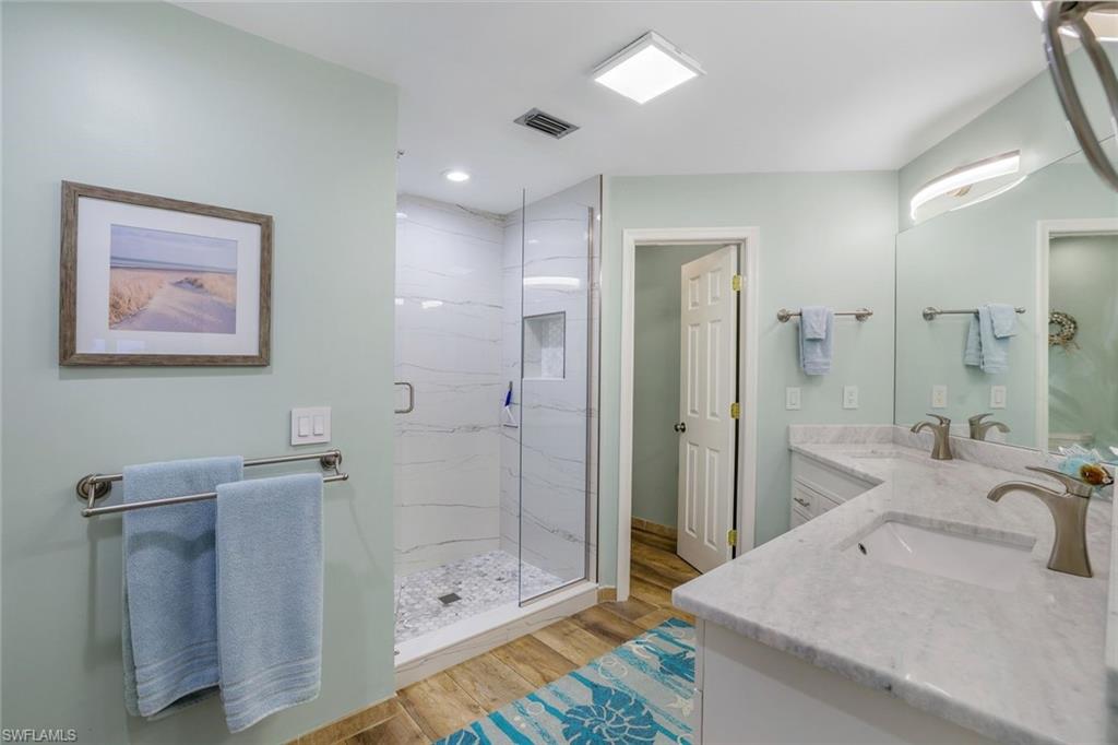 9101 Vanderbilt Drive, Unit 1302 Naples, FL 34108 - Photo 12 of 24 a bathroom with a shower sink and mirror