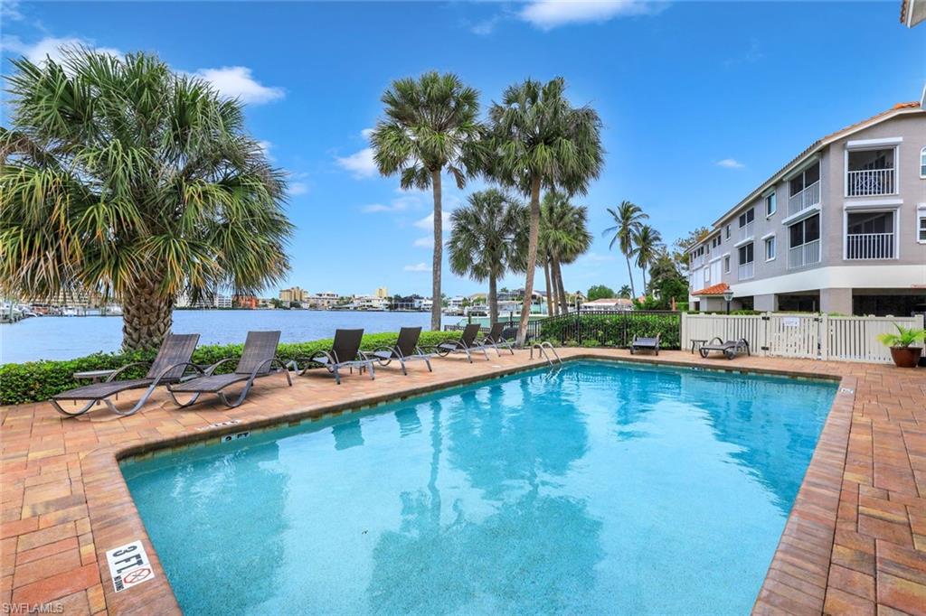 9101 Vanderbilt Drive, Unit 1302 Naples, FL 34108 - Photo 20 of 24 a view of swimming pool with outdoor seating and house in the background