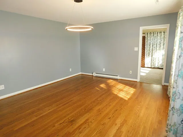 a view of an empty room with a window and wooden floor