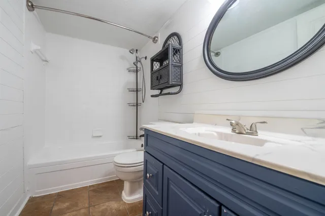 a bathroom with a granite countertop toilet a sink and a mirror