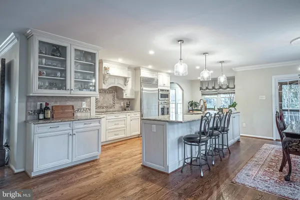 a kitchen with stainless steel appliances kitchen island granite countertop a wooden cabinets a dining table and chairs