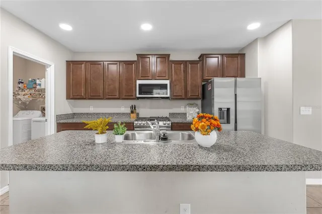 a kitchen with stainless steel appliances granite countertop a sink refrigerator and microwave