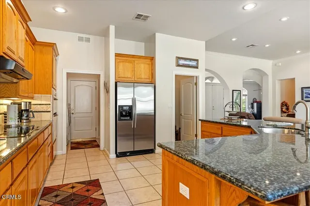 a kitchen with stainless steel appliances granite countertop a refrigerator a stove and a sink with wooden floor