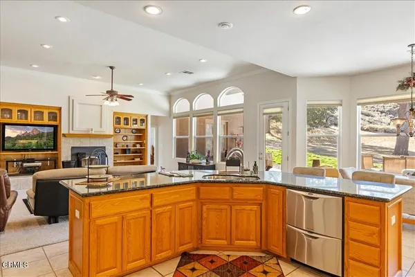 a kitchen with kitchen island granite countertop a refrigerator a sink a stove and a cabinets