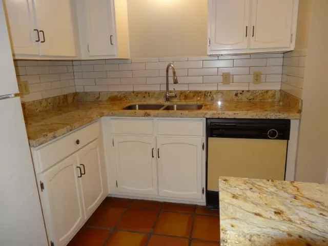 a kitchen with white cabinets and sink