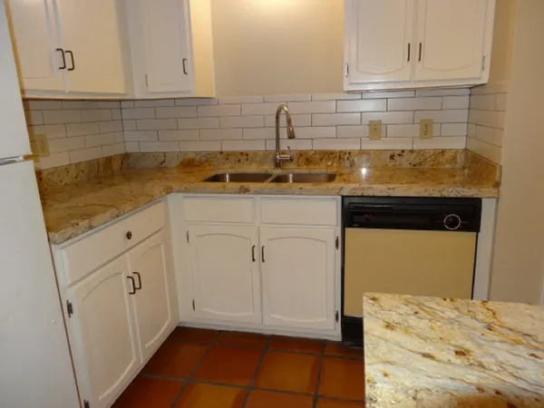 a kitchen with white cabinets and sink