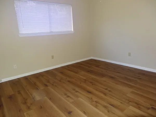a view of an empty room with wooden floor and closet