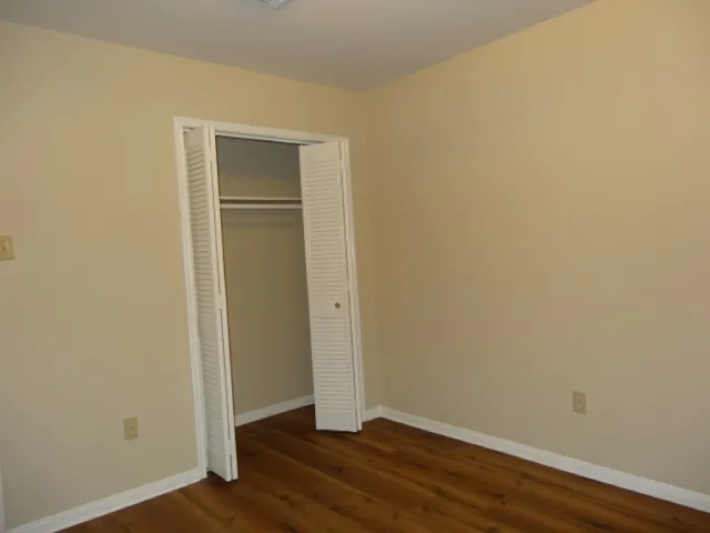 a view of an empty room with wooden floor and closet