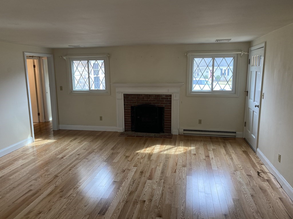 119 Longview Drive Barnstable, MA 02632 - Photo 2 of 5 an empty room with wooden floor a fireplace and windows