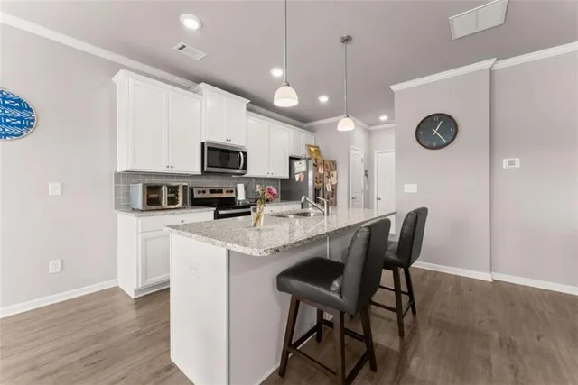 a kitchen with stainless steel appliances granite countertop a stove a refrigerator a microwave a sink a dining table and chairs