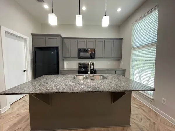 a kitchen with kitchen island granite countertop a sink a counter top space cabinets and stainless steel appliances