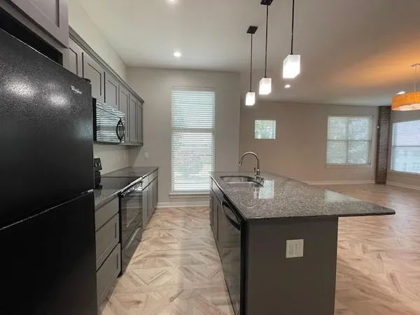 a large kitchen with kitchen island a sink stainless steel appliances and a fireplace