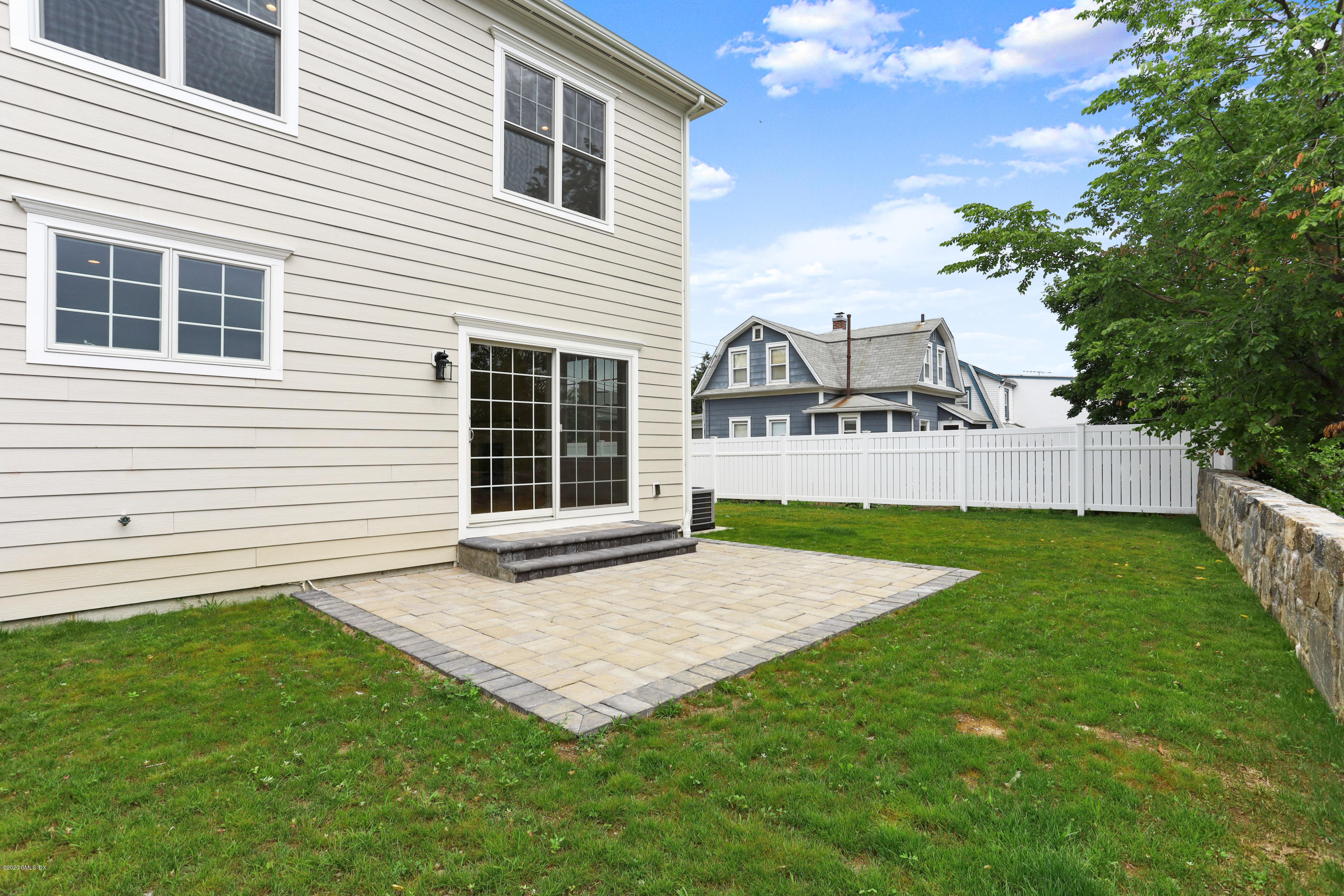 125 Hamilton Avenue, Unit 2 Greenwich, CT 06830 - Photo 17 of 20 a view of a white house in front of a yard with plants and large tree