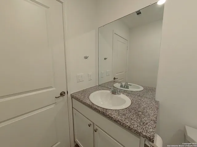a bathroom with a granite countertop sink and mirror