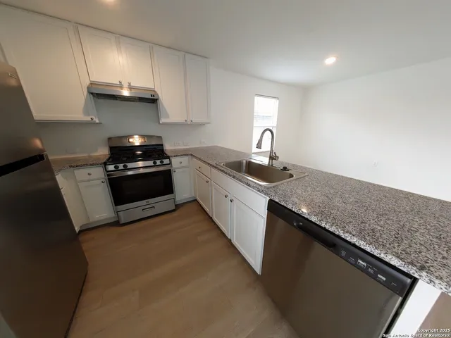 a kitchen with granite countertop a sink dishwasher stove and cabinets