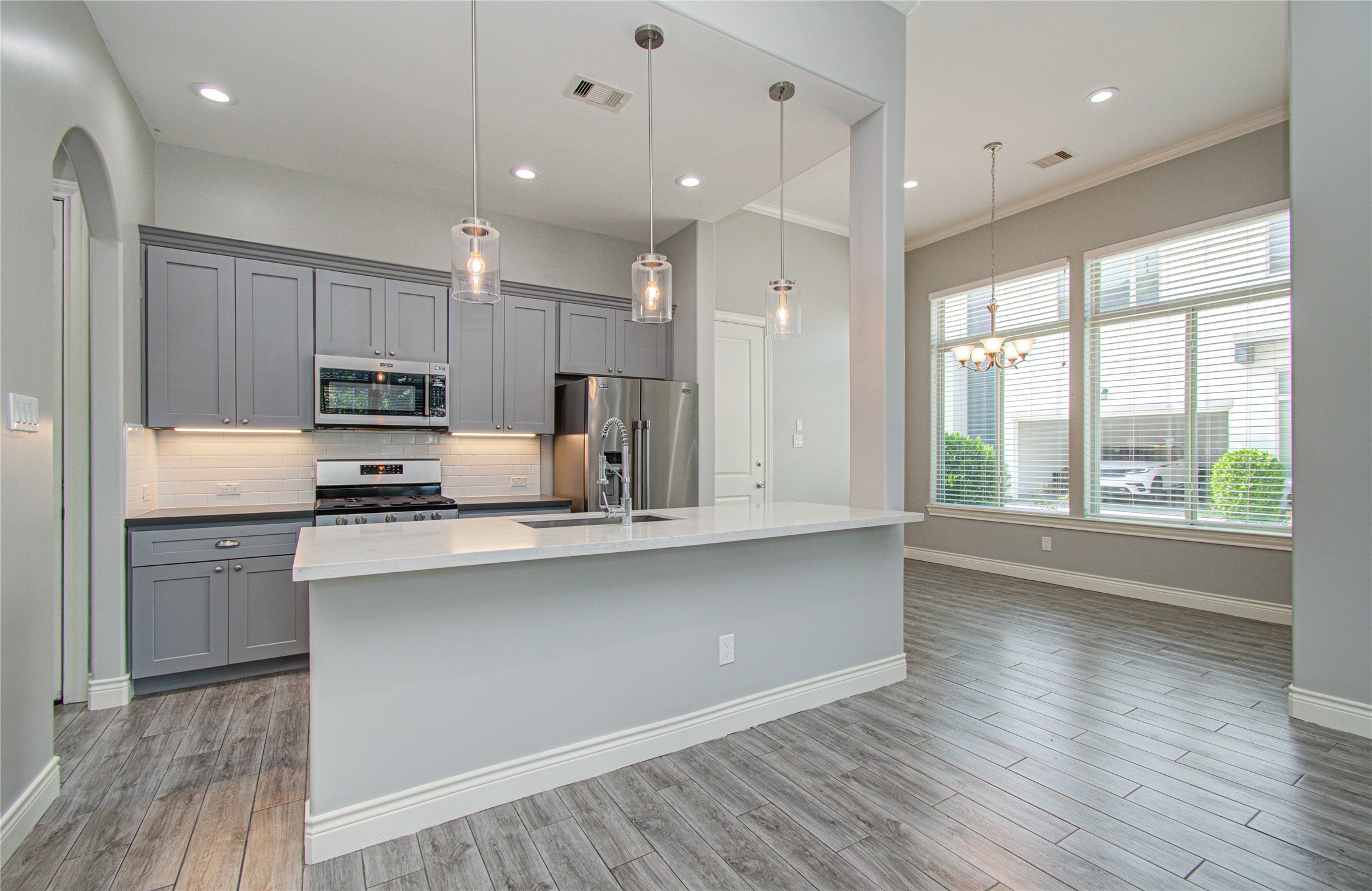8903 Spring Knoll Forest Drive Houston, TX 77080 - Photo 8 of 29 a kitchen with stainless steel appliances granite countertop a sink a microwave oven a refrigerator and white cabinets with wooden floor