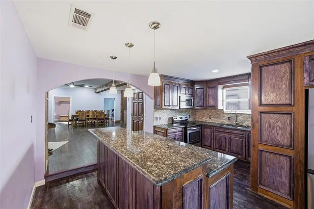 a kitchen with kitchen island granite countertop wooden cabinets and a refrigerator