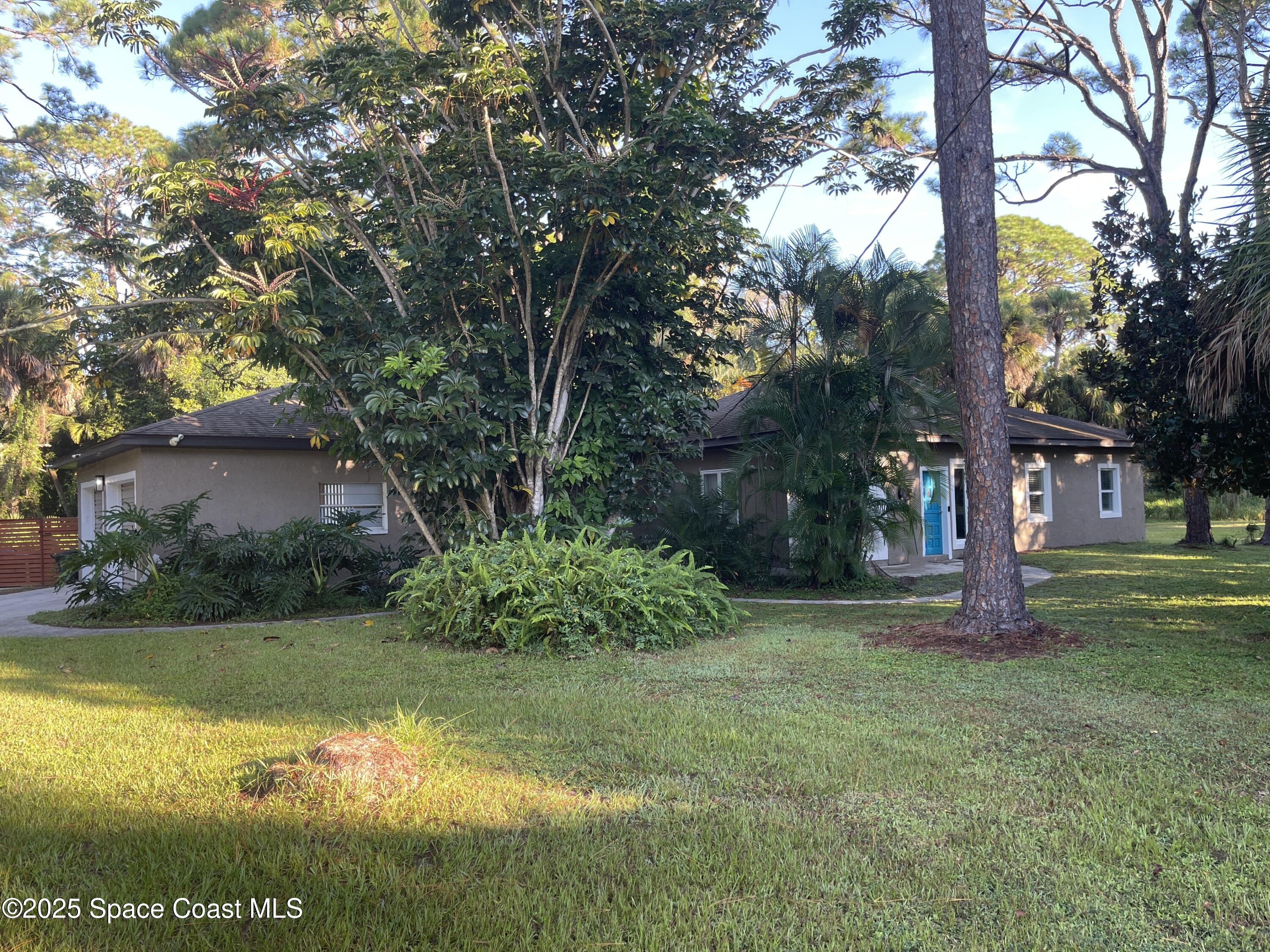 6910 Sheridan Road Melbourne, FL 32904 - Photo 3 of 38 a view of a tree in front of a brick house with large trees