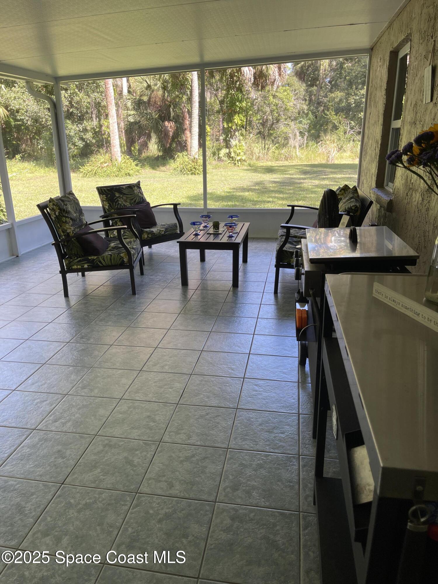 6910 Sheridan Road Melbourne, FL 32904 - Photo 32 of 38 a living room with couches floor to ceiling window next to a yard
