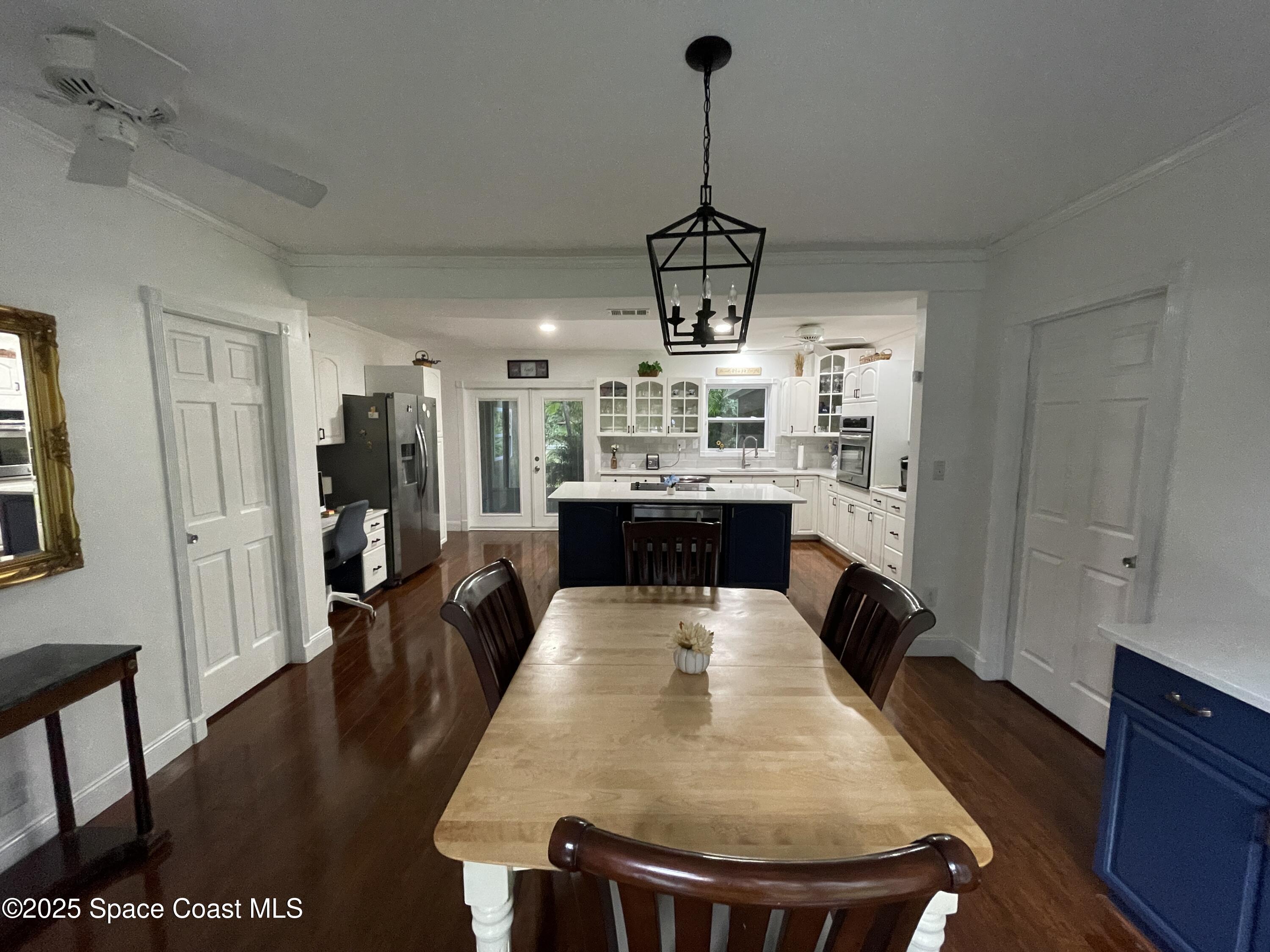 6910 Sheridan Road Melbourne, FL 32904 - Photo 10 of 38 a view of a dining room and livingroom with furniture wooden floor a chandelier
