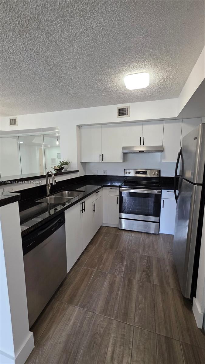 12136 St.Andrews Place, Unit 108 Miramar, FL 33025 - Photo 8 of 43 a large kitchen with wooden floors and black appliances