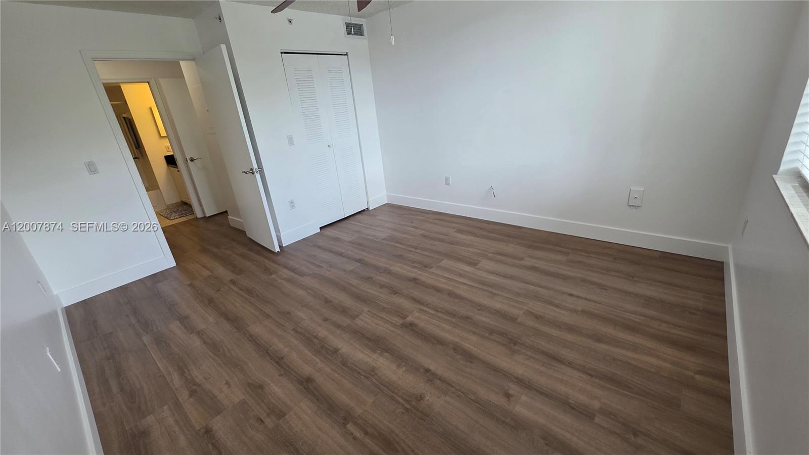12136 St.Andrews Place, Unit 108 Miramar, FL 33025 - Photo 10 of 43 an empty room with wooden floor and mirror