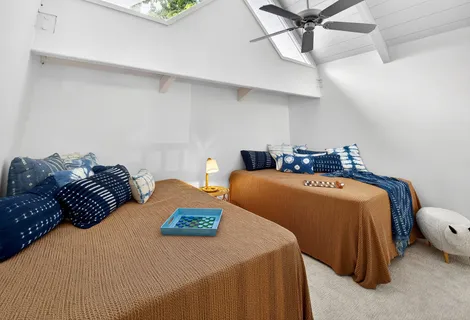 a bedroom with two beds and ceiling fan