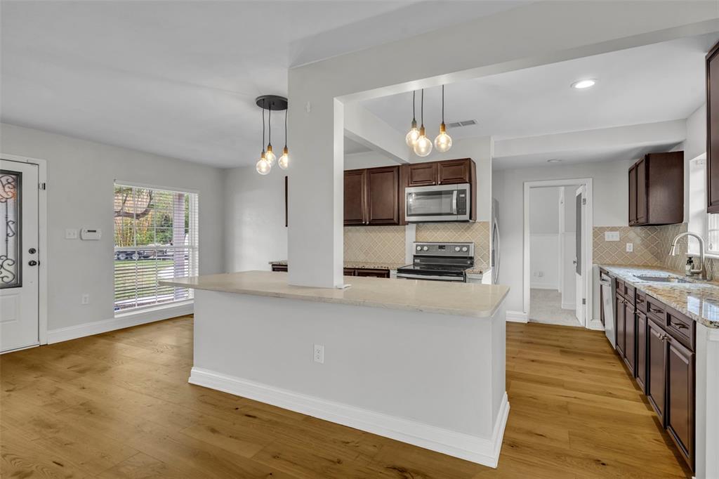 4234 Kendrick Road Orlando, FL 32804 - Photo 12 of 46 a large kitchen with stainless steel appliances a large counter top a stove a sink dishwasher a microwave oven and a granite counter top